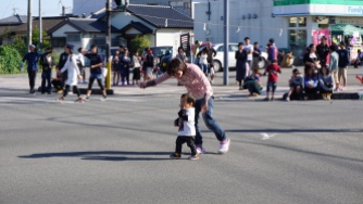 A mom trying to convince her kid that the middle of the street isn't the best place to wait for the parade.